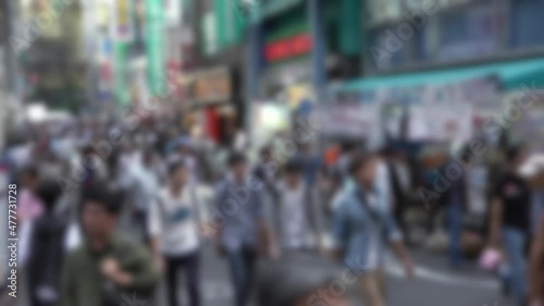 Defocused shot of crowd of people walking in the street at Tokyo Akihabara area, known for electronic and anime stores in Japan. Asian pedestrian shopping in Japanese shops. Blurred background photo