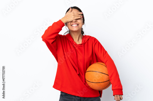 Young woman playing basketball over isolated white background covering eyes by hands and smiling