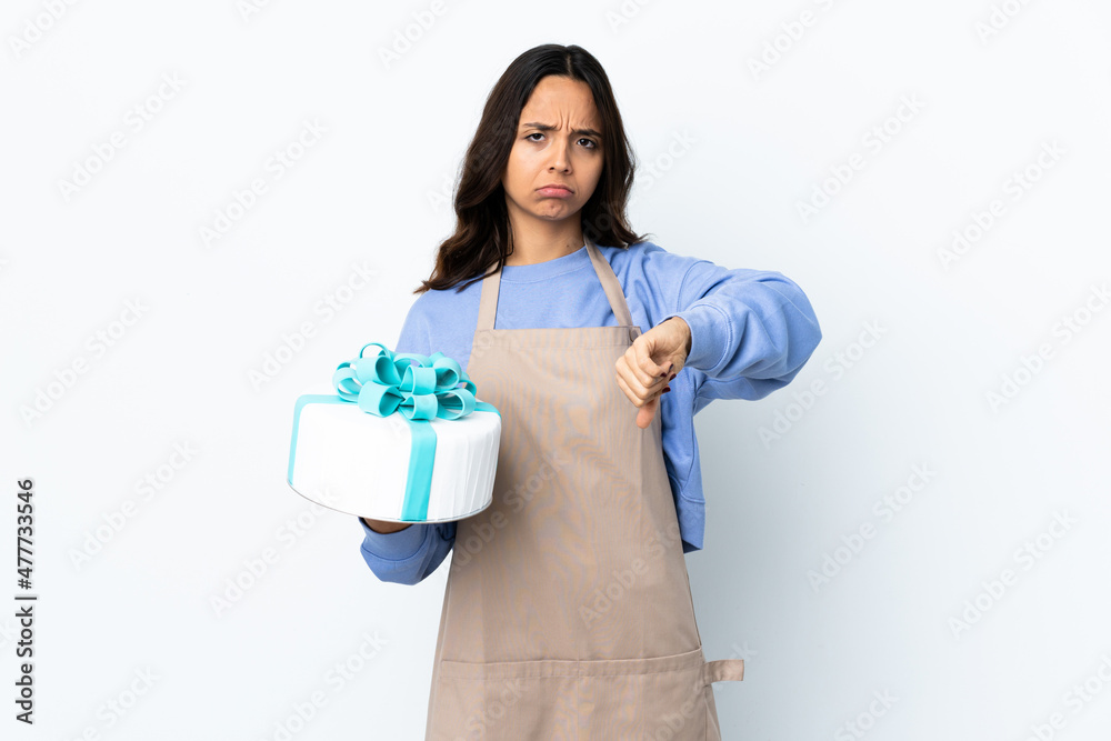 Pastry chef holding a big cake over isolated white background showing thumb down with negative expression Pastry chef holding a big cake over isolated white background showing thumb down with negative expression