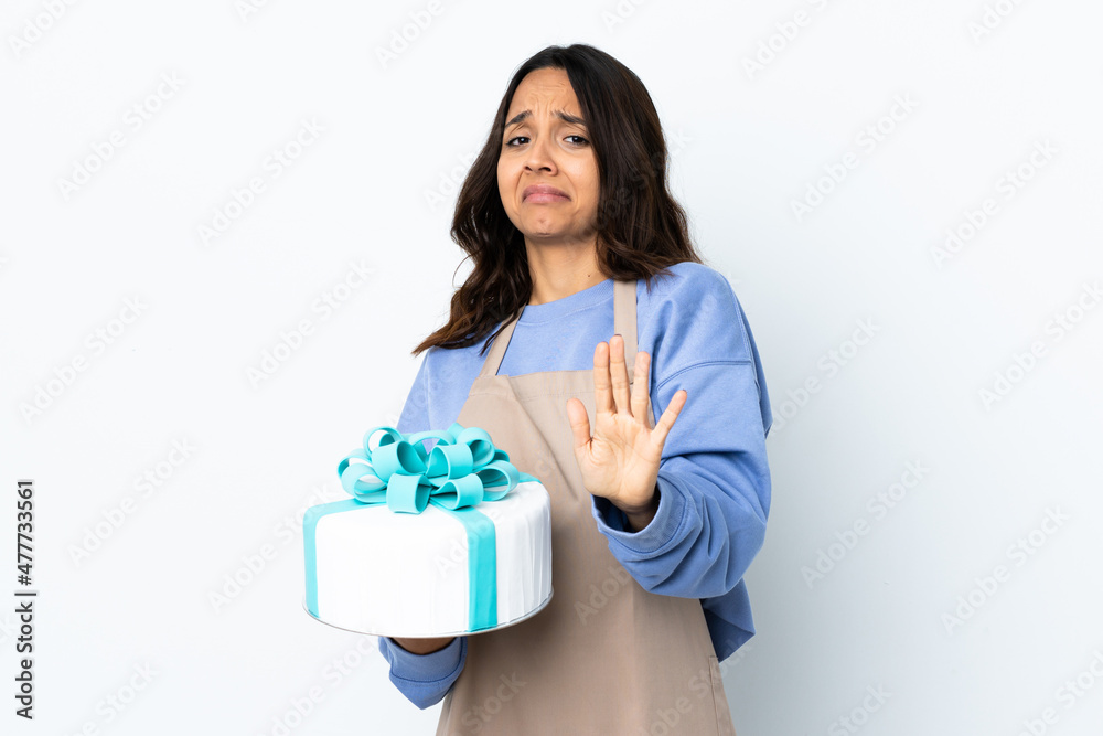 Pastry chef holding a big cake over isolated white background nervous stretching hands to the front Pastry chef holding a big cake over isolated white background nervous stretching hands to the front