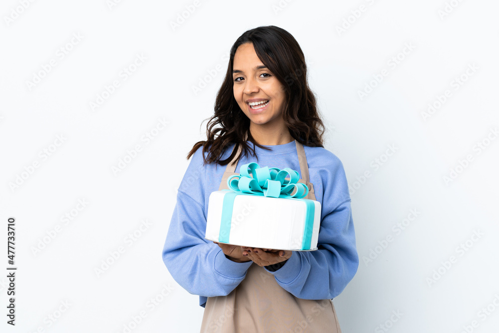 Pastry chef holding a big cake over isolated white background keeps palm together. Person asks for something Pastry chef holding a big cake over isolated white background keeps palm together. Person asks for something