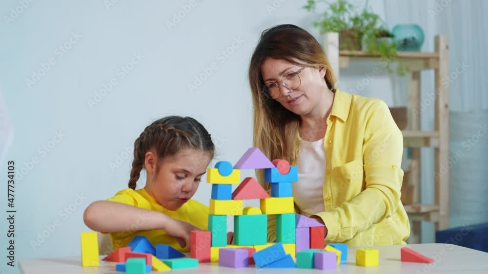 mom and daughter play with cubes a toys blocks indoor. childhood kindergarten kid happy family concept. mom and daughter play with blocks cubes builds a house. kid playing toys. happy family mom and daughter play with cubes a toys blocks indoor. childhood kindergarten kid happy family concept. mom and daughter play with blocks cubes builds a house. kid playing toys. happy family