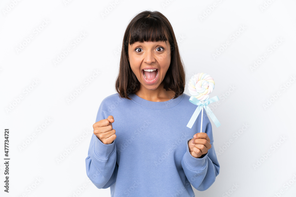 Young mixed race woman holding a lollipop isolated on white background celebrating a victory in winner position Young mixed race woman holding a lollipop isolated on white background celebrating a victory in winner position