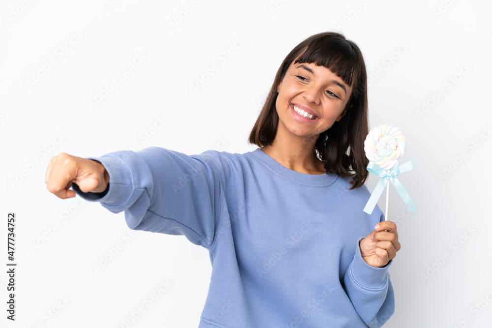 Young mixed race woman holding a lollipop isolated on white background giving a thumbs up gesture Young mixed race woman holding a lollipop isolated on white background giving a thumbs up gesture