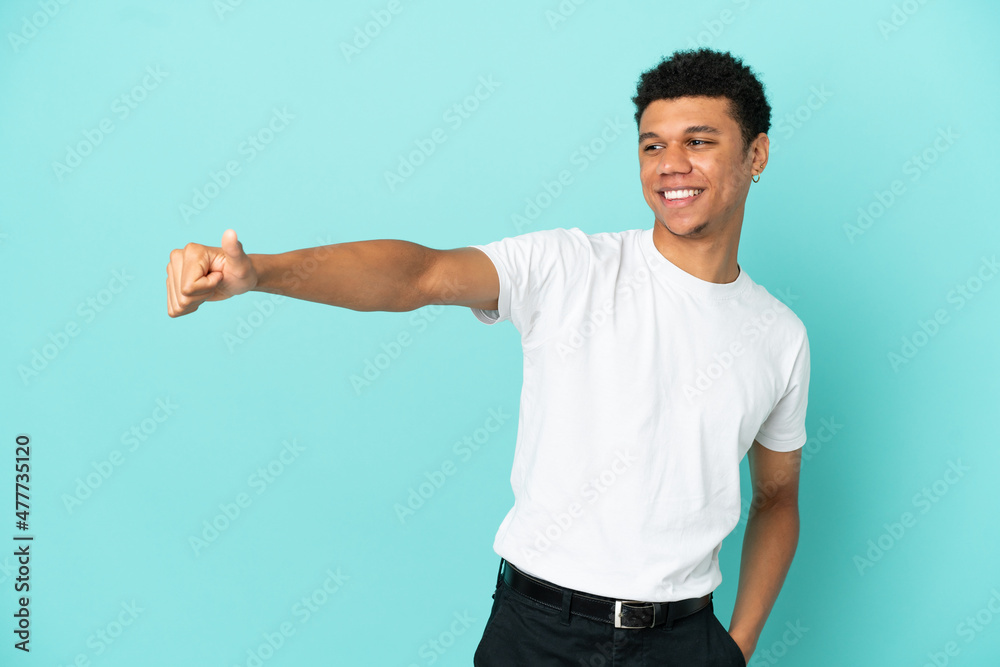Young African American man isolated on blue background giving a thumbs up gesture Young African American man isolated on blue background giving a thumbs up gesture