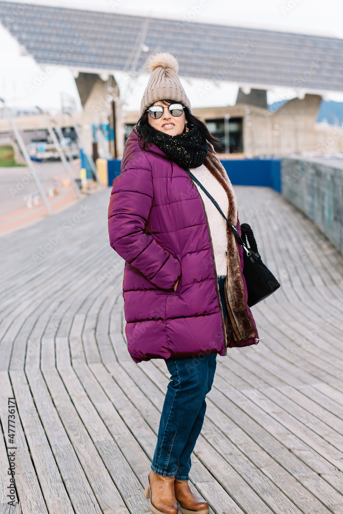 Obraz premium portrait of a smiling woman with sunglasses and wool cap on a sunny autumn day walking in the city