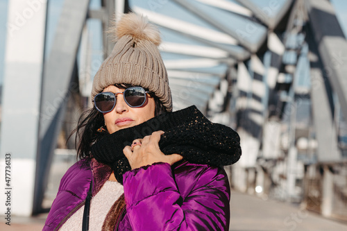portrait of a smiling woman with sunglasses and wool cap on a sunny autumn day walking in the city
