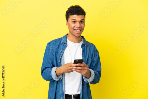 Young African American man isolated on yellow background surprised and sending a message