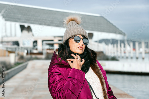 portrait of a woman with sunglasses and wool cap on a sunny autumn day walking in the city