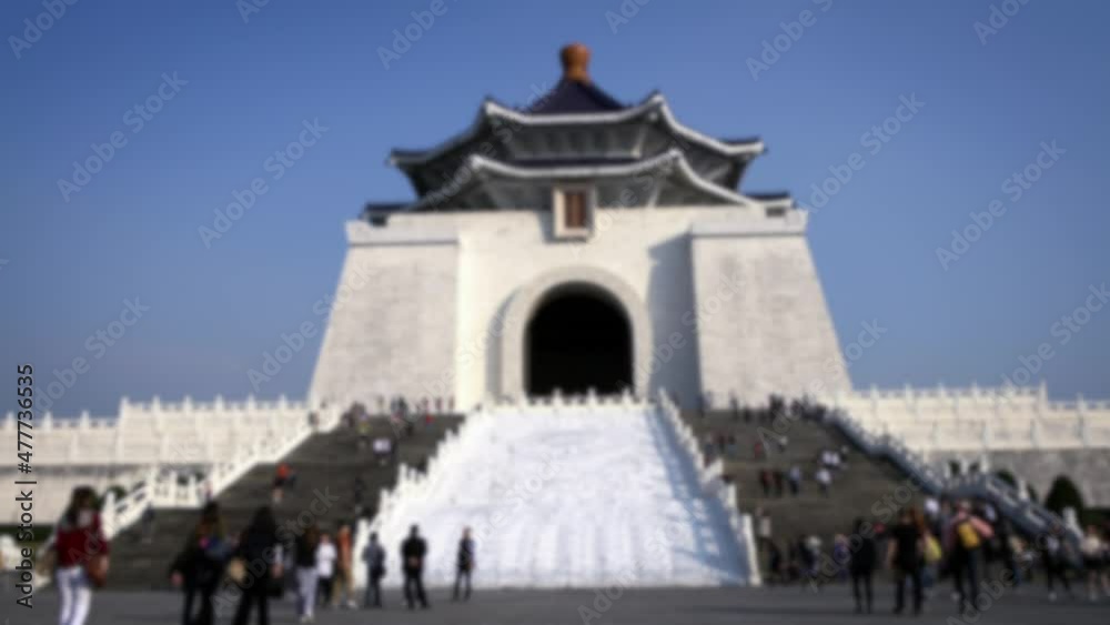 Blurred defocused view of people walking around the entrance gate to National Music Hall and the Chiang Kai Shek memorial hall in beautiful sunny day in Taipei, Taiwan