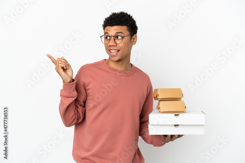 Young African American man holding a burger and pizzas isolated on white background intending to realizes the solution while lifting a finger up