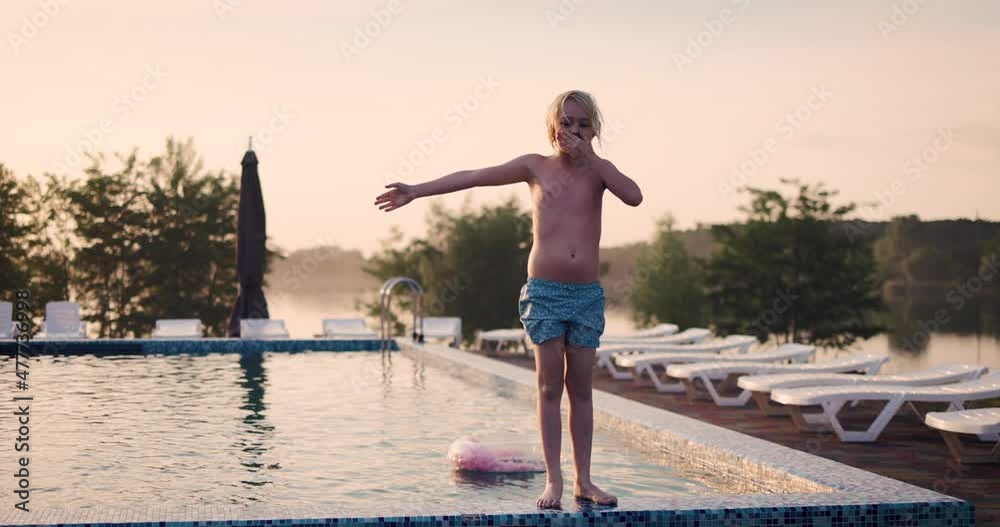 happy young boy, excited kid having fun at the water park resort, jumping in water at sunset happy young boy, excited kid having fun at the water park resort, jumping in water at sunset