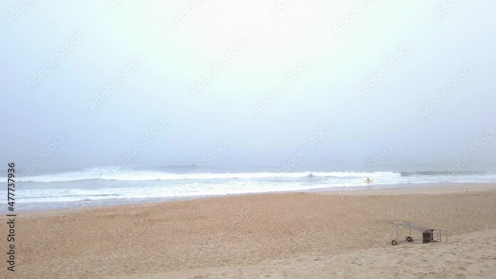 Pan left and large view from a foggy beach with many surfers in the sea Pan left and large view from a foggy beach with many surfers in the sea