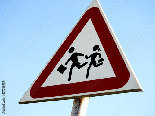 Selective focus of a school crossing sign at the side of the road to inform drivers to be alert of children crossing the street, school children warning crossing road sign, caution kids crossing photo