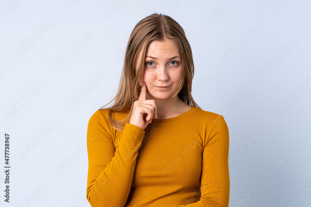 Teenager Ukrainian girl isolated on blue background and thinking Teenager Ukrainian girl isolated on blue background and thinking
