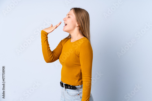 Tableau sur toile Teenager Ukrainian girl isolated on blue background yawning and covering wide op