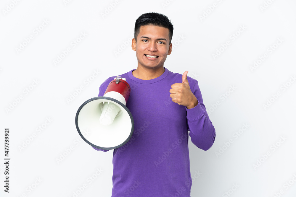 Young Ecuadorian man isolated on white background holding a megaphone with thumb up Young Ecuadorian man isolated on white background holding a megaphone with thumb up