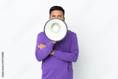 Young Ecuadorian man isolated on white background shouting through a megaphone to announce something