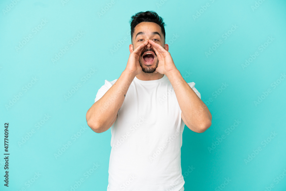 Young caucasian man isolated on blue background shouting and announcing something Young caucasian man isolated on blue background shouting and announcing something