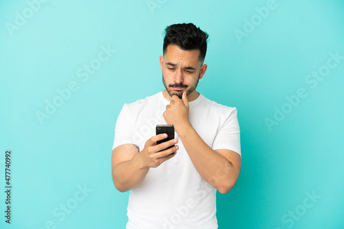 Young caucasian man isolated on blue background thinking and sending a message
