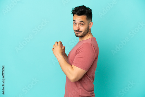 Young caucasian man isolated on blue background scheming something