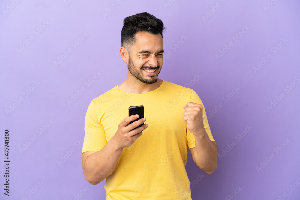 Young caucasian man isolated on purple background with phone in victory position Young caucasian man isolated on purple background with phone in victory position