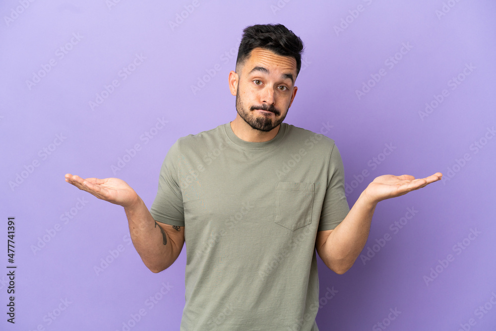Young caucasian man isolated on purple background making doubts gesture Young caucasian man isolated on purple background making doubts gesture