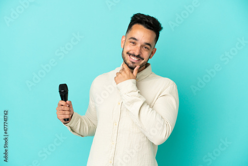 Young caucasian singer man isolated on blue background happy and smiling © luismolinero