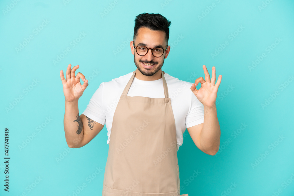 Restaurant waiter caucasian man isolated on blue background showing an ok sign with fingers Restaurant waiter caucasian man isolated on blue background showing an ok sign with fingers