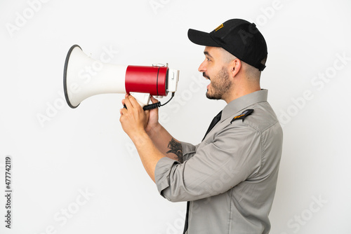 Young security caucasian man isolated on white background shouting through a megaphone