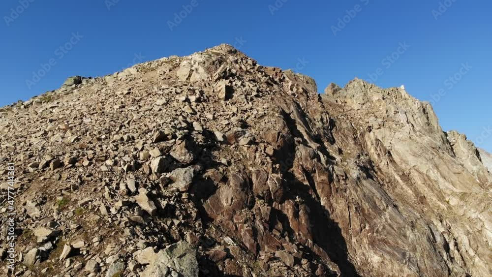Aerial view of flight around a cliff top high in the mountains at day. Against the background of snow-capped peaks. Dynamic aerial view of uninhabited rocks travel 4k video Aerial view of flight around a cliff top high in the mountains at day. Against the background of snow-capped peaks. Dynamic aerial view of uninhabited rocks travel 4k video