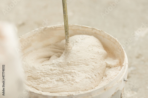 the process of mixing plaster mortar putty mixer in a bucket close-up.