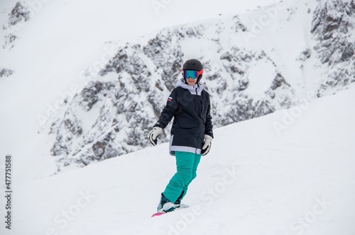 a girl on a snowboard rides down the side of the mountain