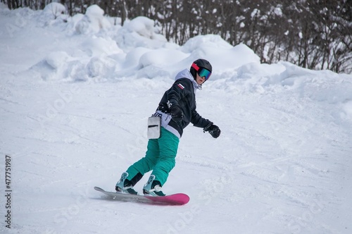 a girl on a snowboard rides down the side of the mountain