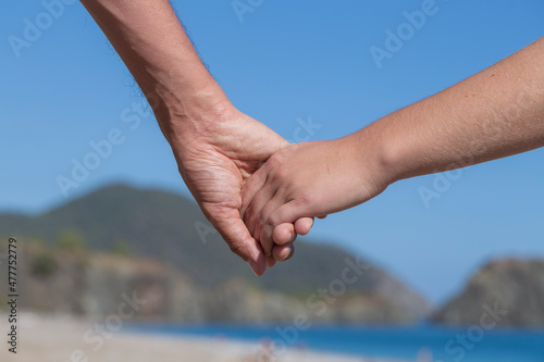 Couple hands held together on a natural sea background, close up © OlegD