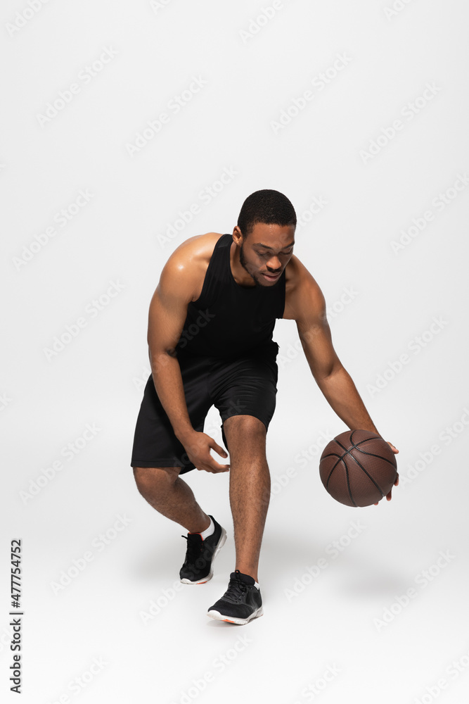 full length of african american man playing basketball on grey. full length of african american man playing basketball on grey.