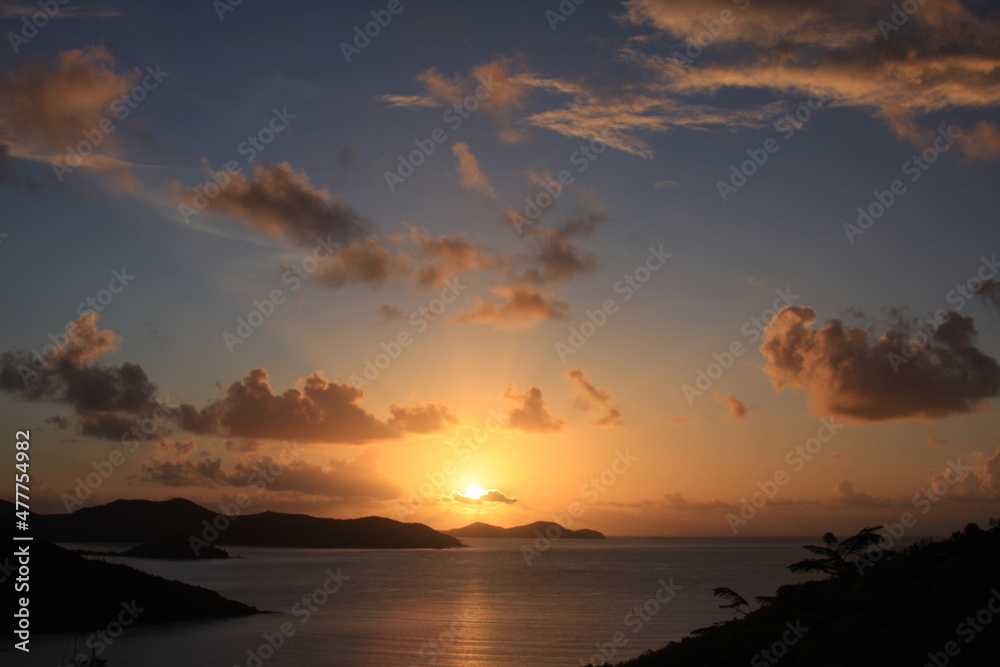 Tropical sunset over the mountains and water. Blues and oranges with clouds in sky make relaxing and calm feelings.  Taken in St. John USVI in beautiful Caribbean. 