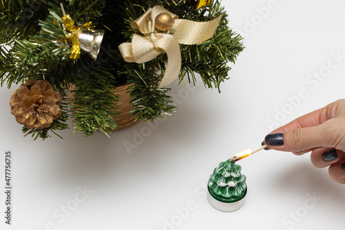 Christmas candle that is lit with a match holding it in hand photo