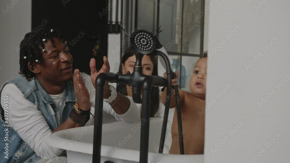 Baby bath. Mixed race baby playing in a bath with caucasian mother and african american father. High quality 4k footage Baby bath. Mixed race baby playing in a bath with caucasian mother and african american father. High quality 4k footage