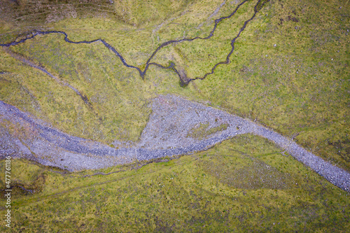 Fototapeta Naklejka Na Ścianę i Meble -  Aerial view of a dry river crossing a green meadow