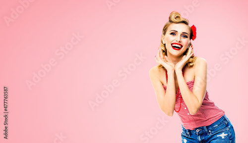 Excited surprised, very happy beautiful woman. Pin up girl with open mouth and raised hands showing toothy smile. Retro and vintage concept. Rose pink background. © vgstudio