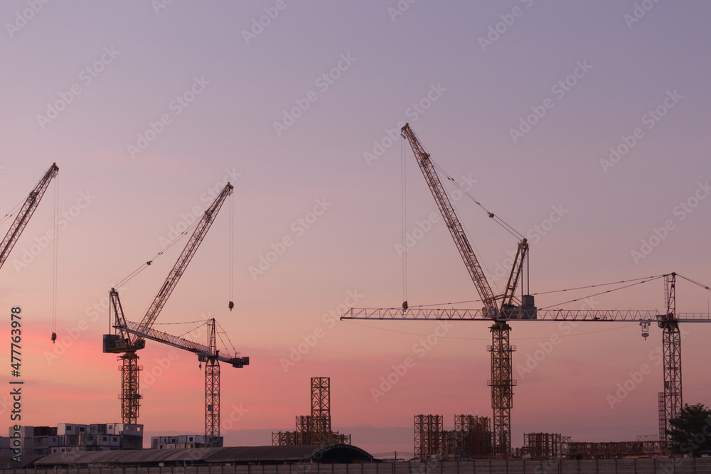 White containers, yellow steel tower cranes, near green fields,