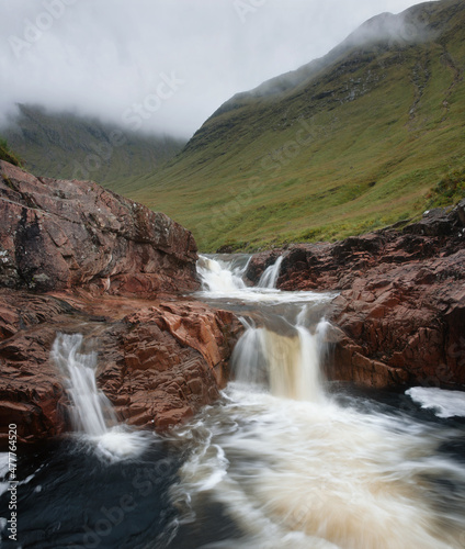 Small mountain river with waterfalls and mountains covered with clouds. River Etive  Highlands  Scotland