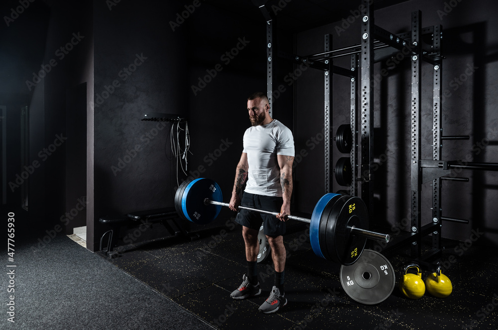 Foto Stock Young active strong sweaty muscular fit man with big muscles  doing hardcore deadlift or weightlift workout cross training with heavy  barbell weights in the gym. Male sportperson strength lifting