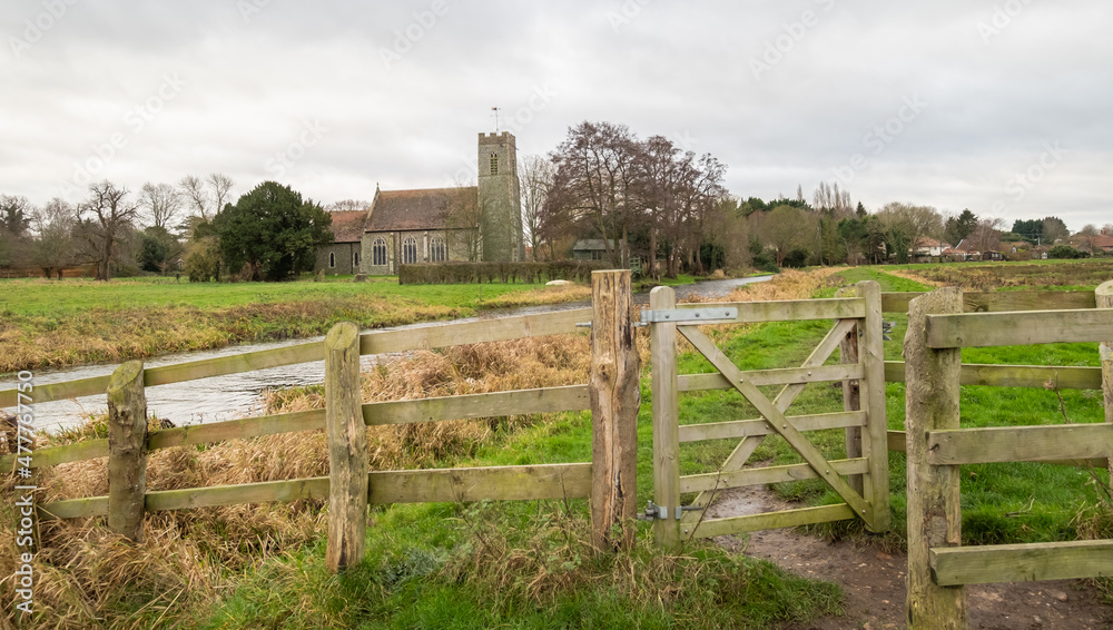 A wooden fence and gate securing entry and exit to the public footpath along the River Bure in the Norfolk village of Buxton. Captured during the winter