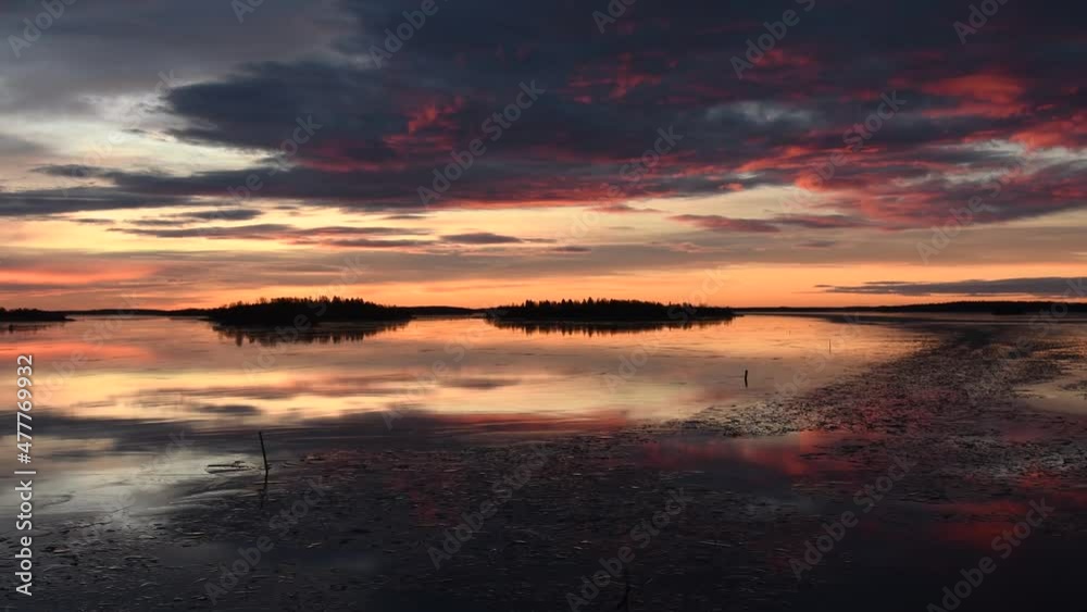 Tranquil winter morning by the lake with a beautiful sunrise. Colors of the sky reflecting in the thin ice on the frozen water. Footage made in Västerås, Sweden. Tranquil winter morning by the lake with a beautiful sunrise. Colors of the sky reflecting in the thin ice on the frozen water. Footage made in Västerås, Sweden.