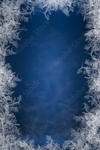 Frosty frame. Decorative ice crystals frame on dark blue background