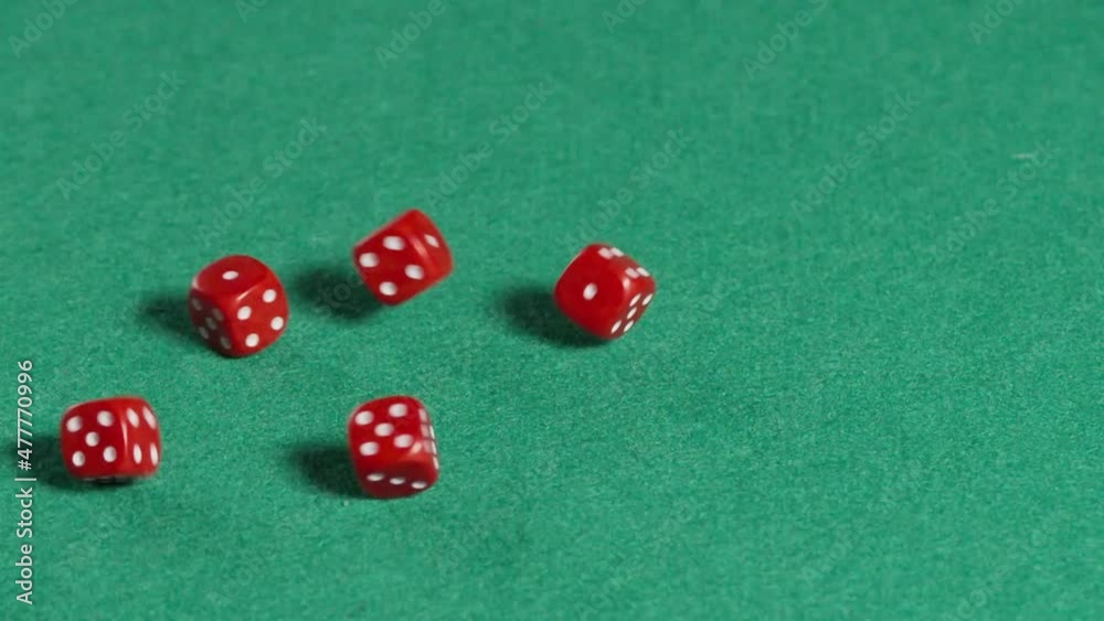 Five red dices rolling in slow motion on a green mat. Five red dices rolling in slow motion on a green mat.