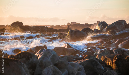 Dreamy ocean waves crashing on a rocky beach at sunset in Jacobsbaai, South africa. photo