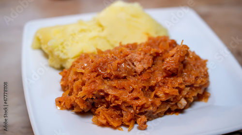 bigos with potatoes on a white plate